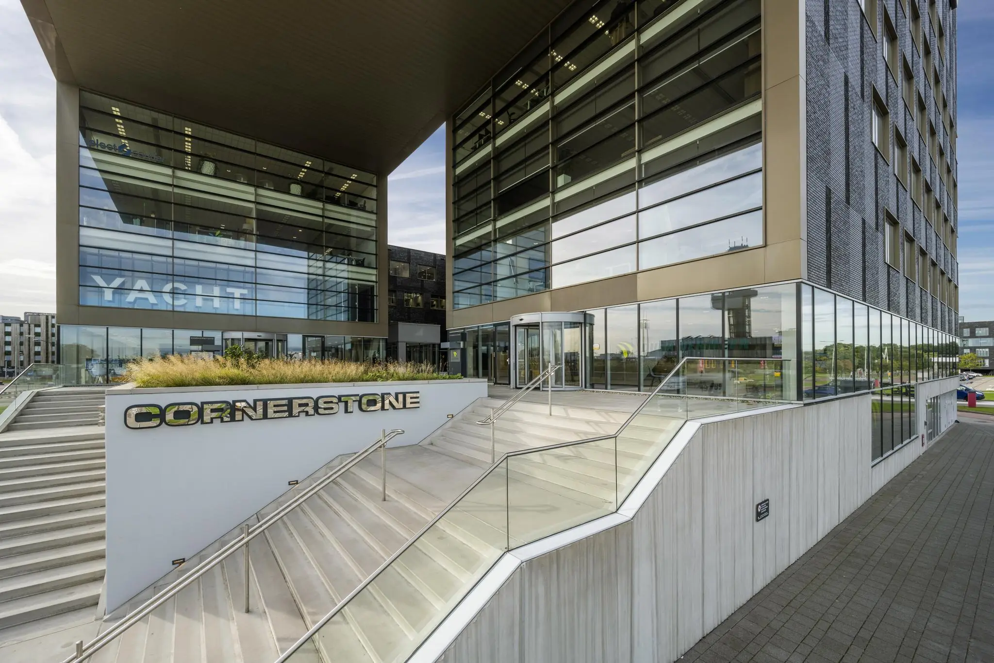 Moderne kantoorgebouw Cornerstone aan het Airportplein in Rotterdam met glazen gevel en trapopgang.
